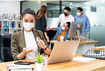 Asiatische Büroangestellte tragen Schutzmaske mit Alkoholtupfer für Hygiene und Handdesinfektion im neuen Normalbüro 